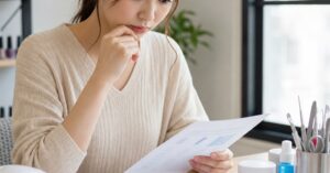 群馬でネイルケアスクールを選ぶ女性が、ネイル用品と費用資料を確認している様子